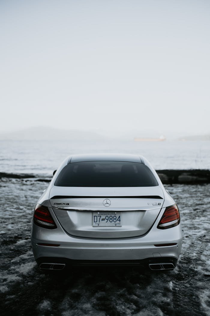Rear view of a sleek Mercedes Benz parked by the coast on a serene day.